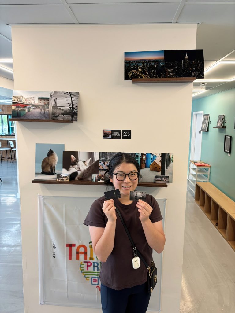 Hiroko standing in front of her photographs in a cat cafe