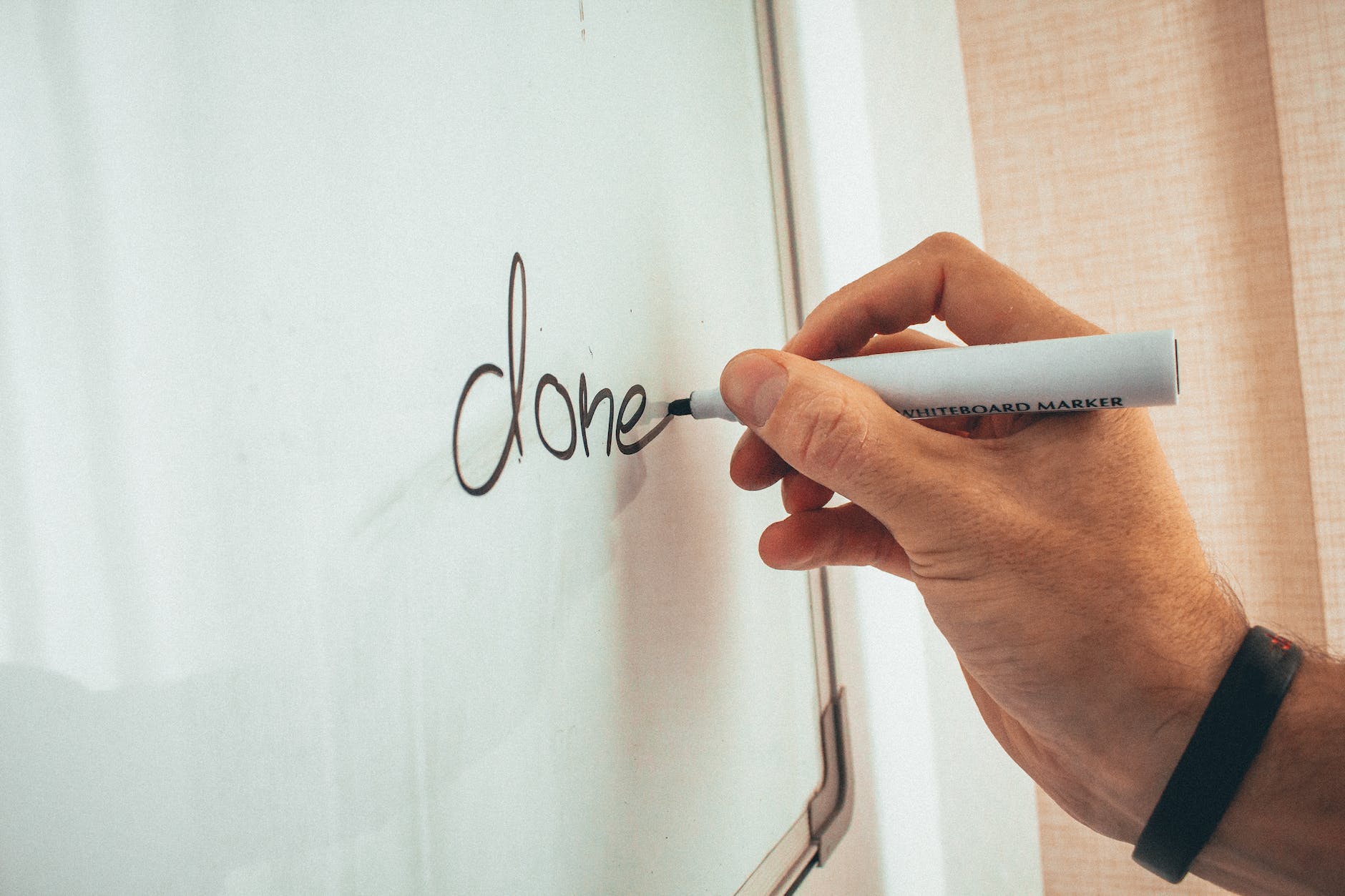 crop man writing on whiteboard in modern office